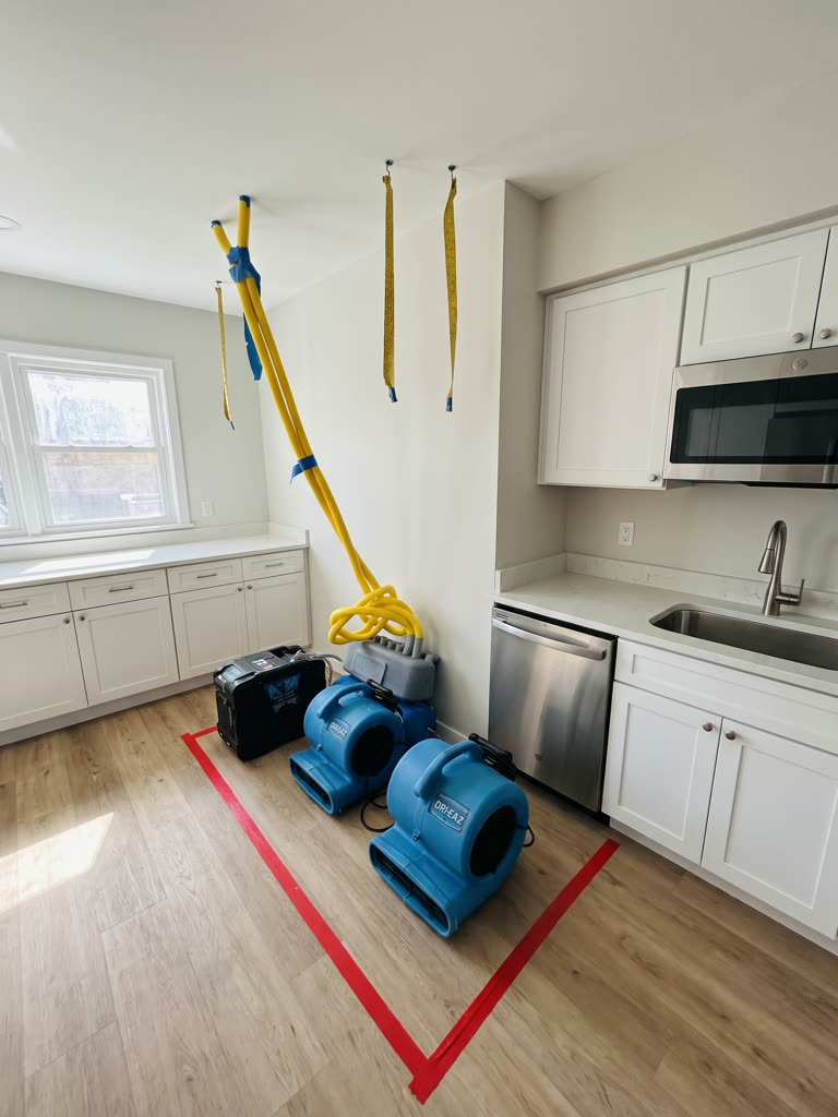 Commercial air movers drying a kitchen floor